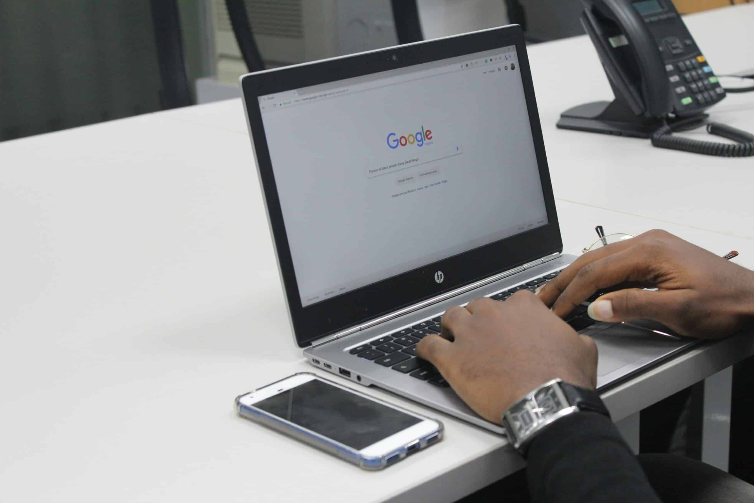 Hands typing on a laptop with Google search page open.
